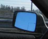 Automobilio Audi 80 veidrodėlis ir matomas per jį gatvės žibintas